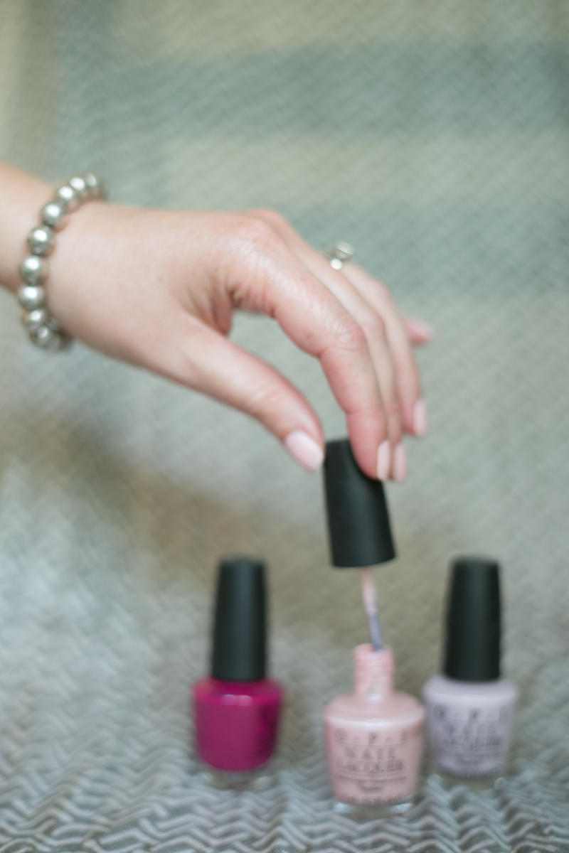 A woman's hand reaching for a bottle of nail polish.