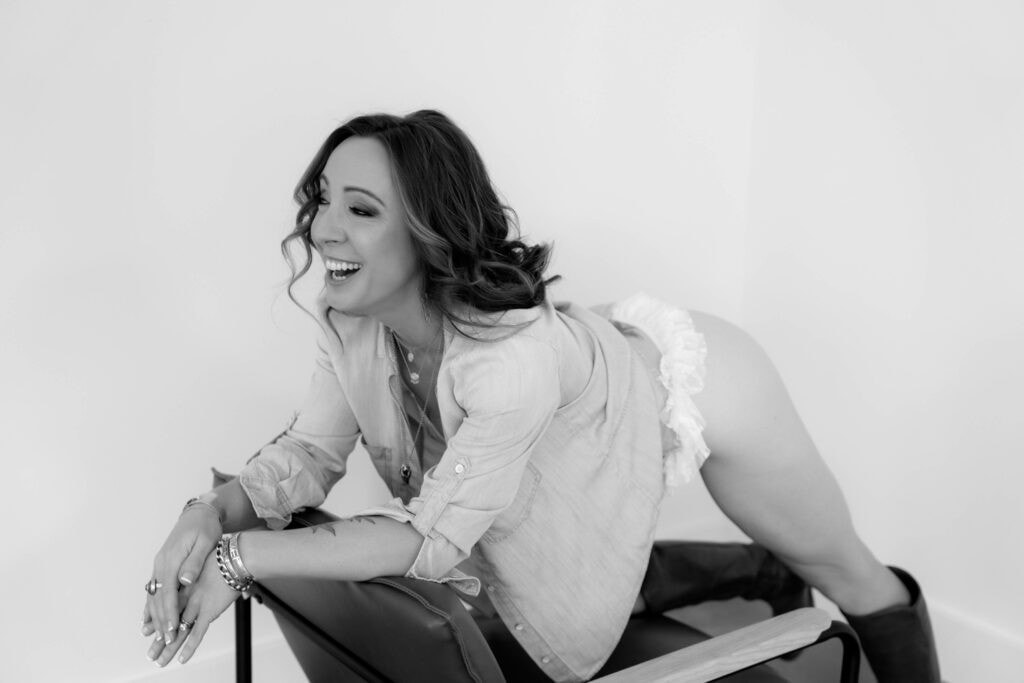 A woman is posing on a chair in a black and white photo.