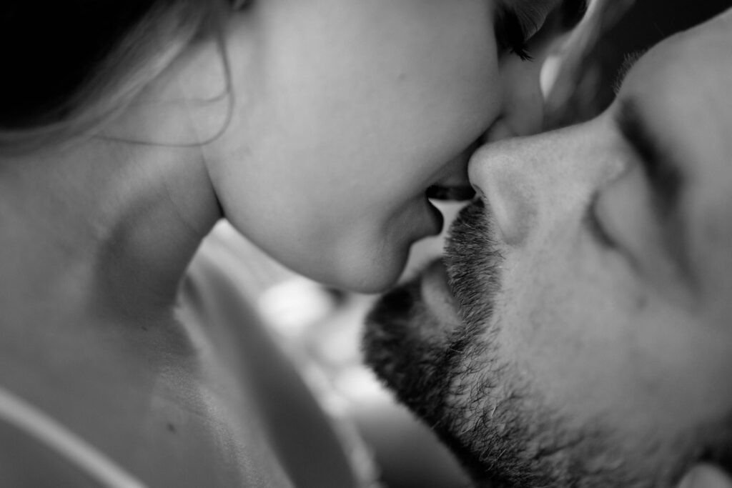 Close-up of a man and woman about to kiss, focusing on their nearly touching lips. the image is in black and white, emphasizing their intimate moment.