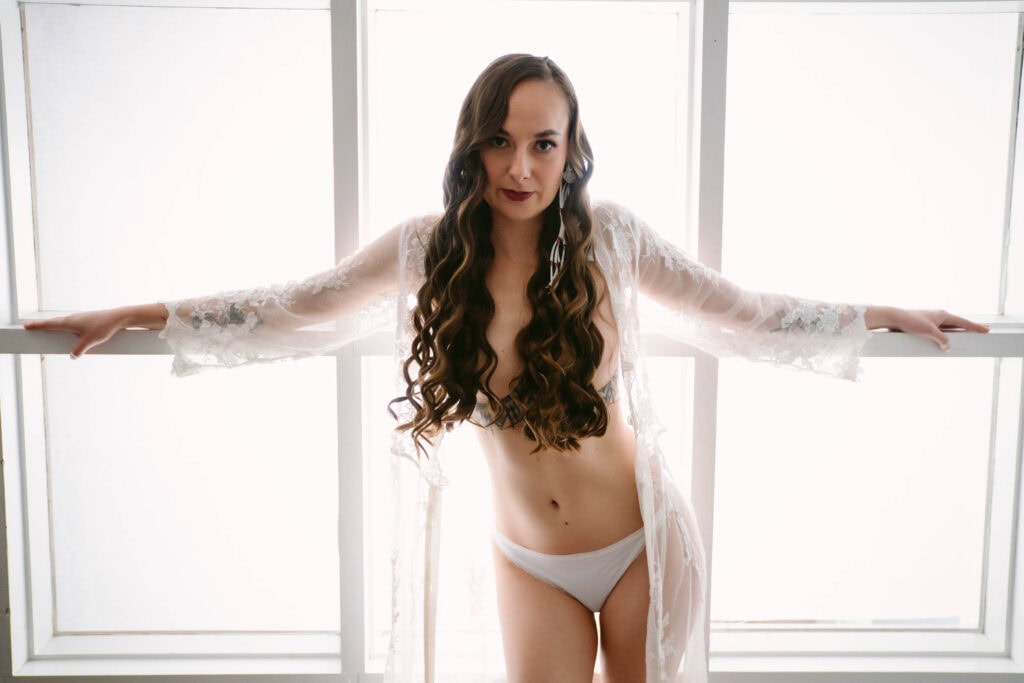 Woman in lingerie standing by a window.
