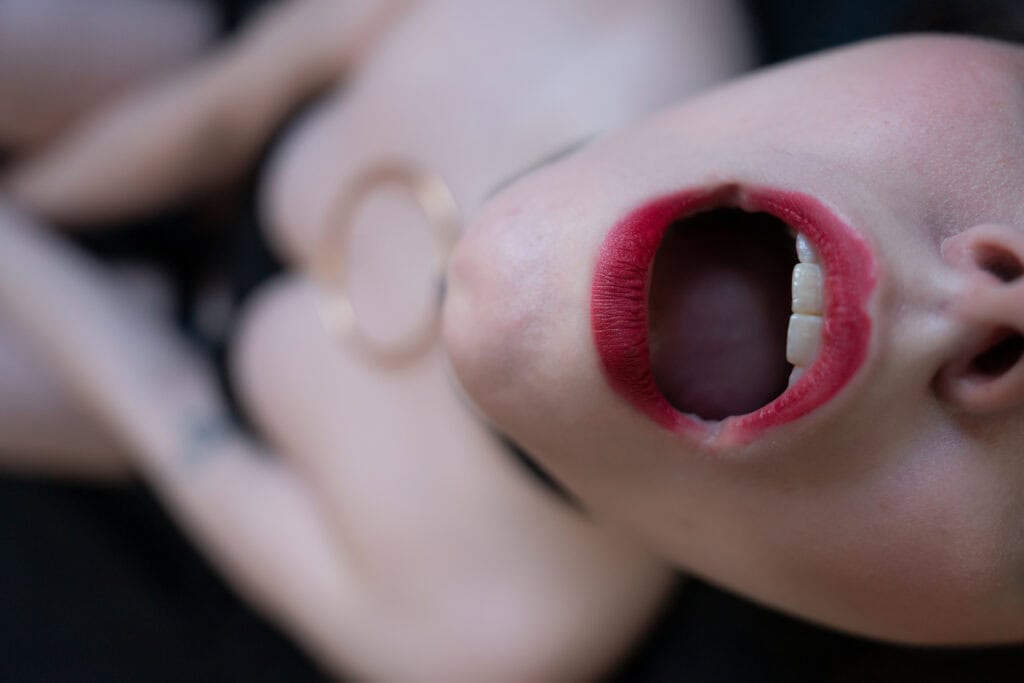 Person with red lipstick and open mouth close-up.