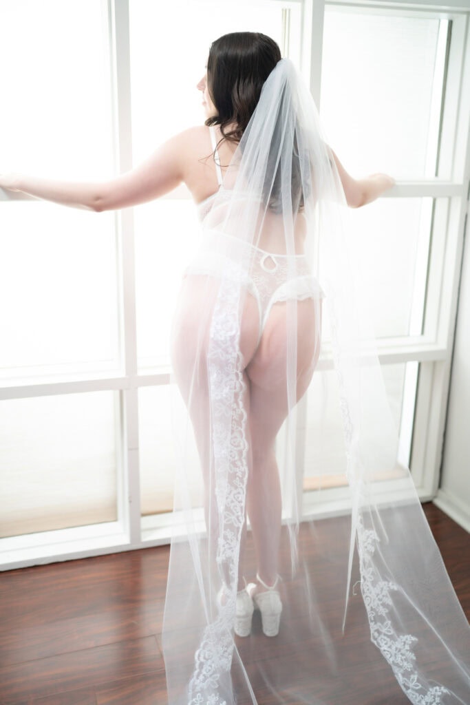 Bride in lingerie and veil by window