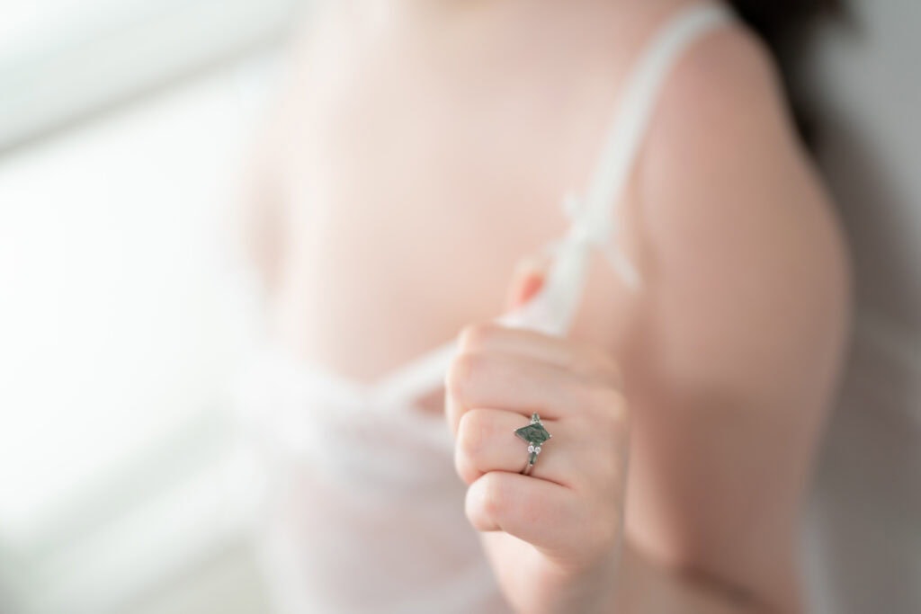 Hand displaying emerald ring on finger.
